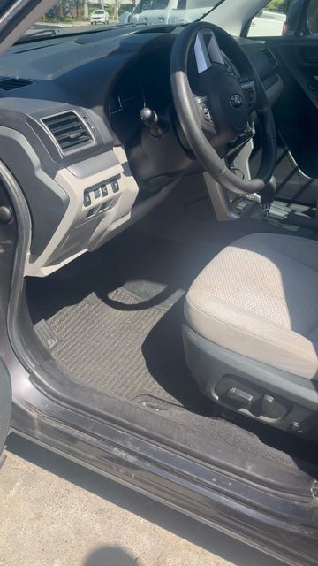 Subaru driver area after cleaning, with a clean floor mat and an empty seat