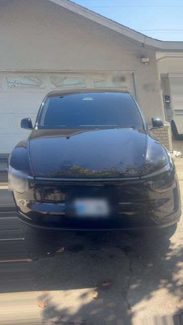 Black Tesla Model Y after washing, with glossy paint reflecting the sky