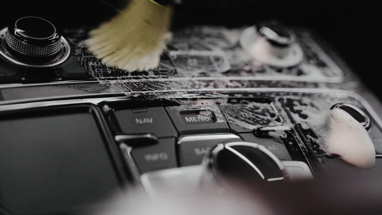 Stock photo: a soft detailing brush working foam around car console buttons
